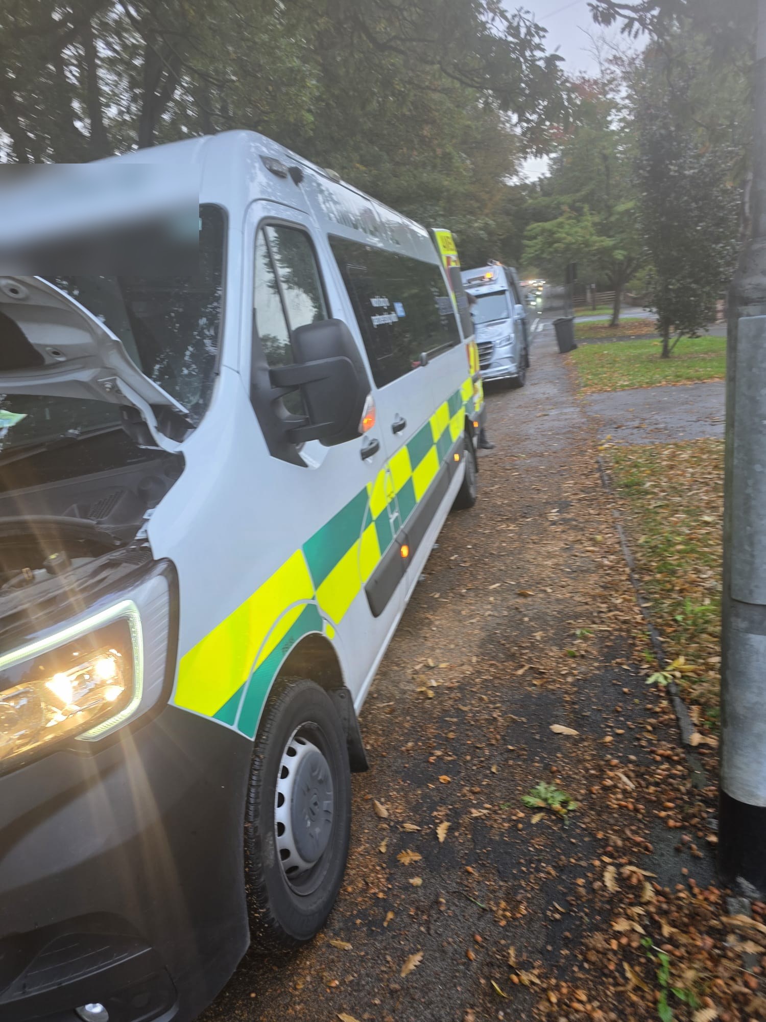 An ambulance with the bonnet up being repaired, with an ALD service van alongside