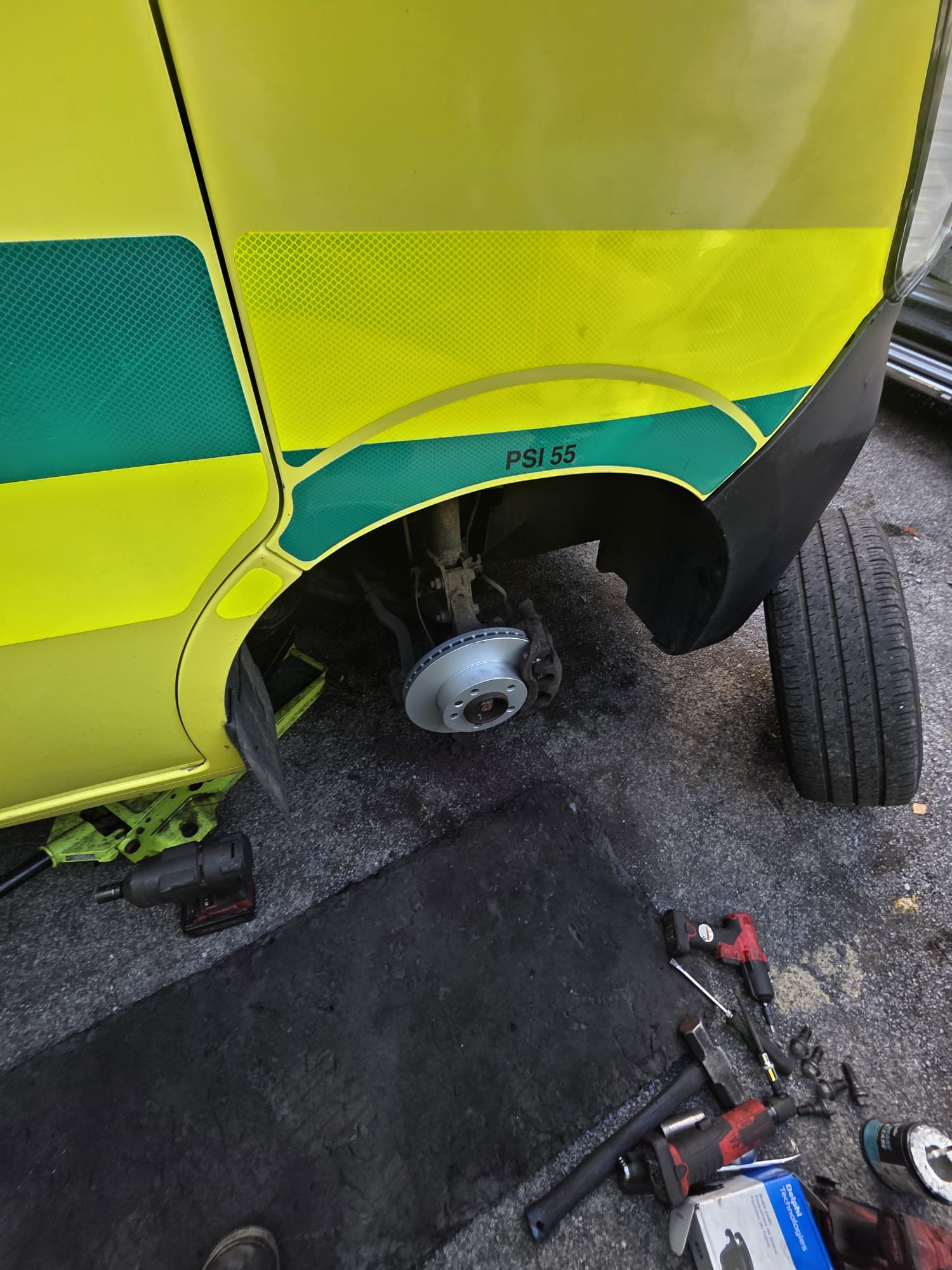 Close-up of a brake job on the wheel arch of a yellow ambulance