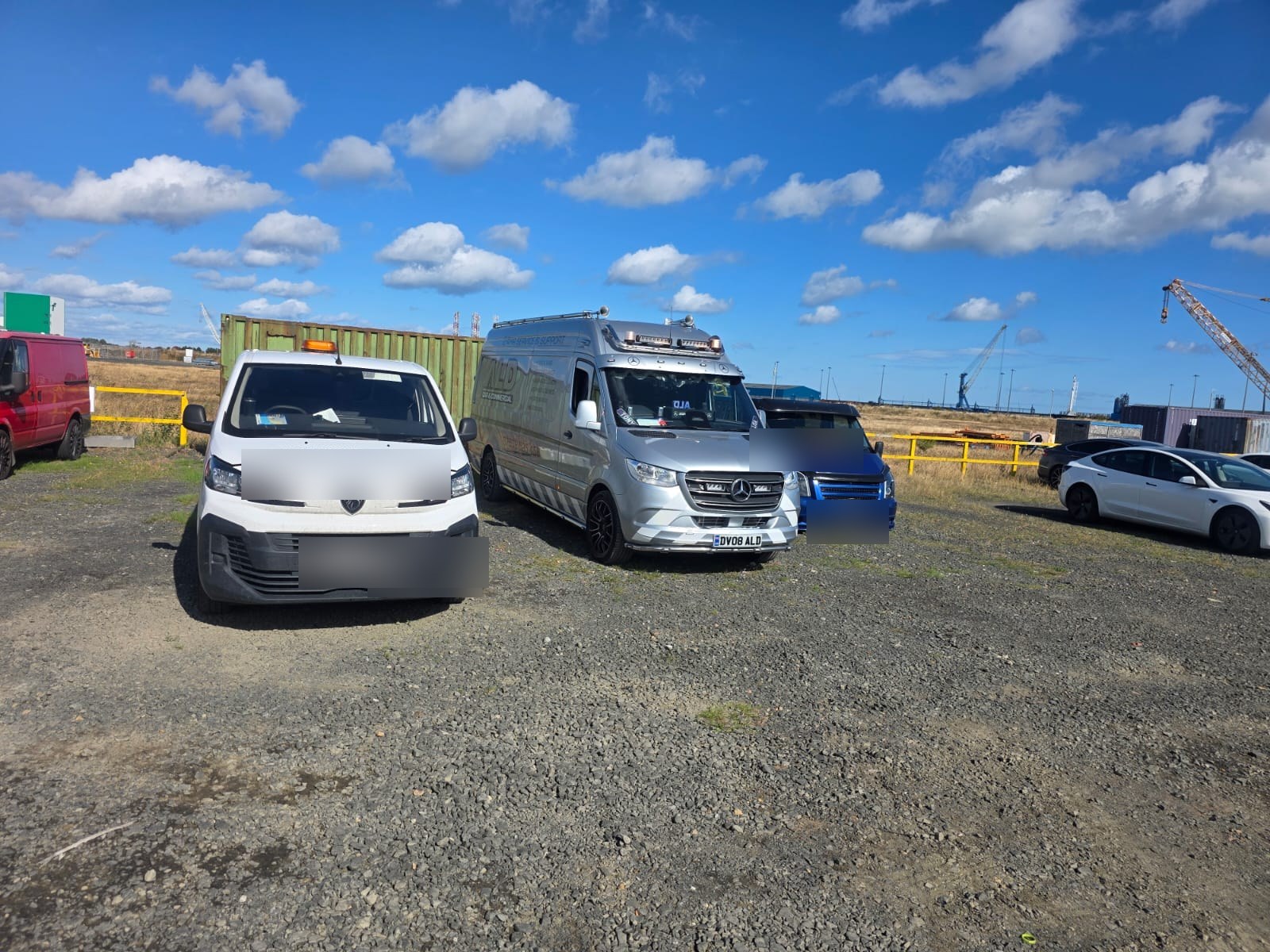 An ALD van parked between working vehicles at an industrial yard