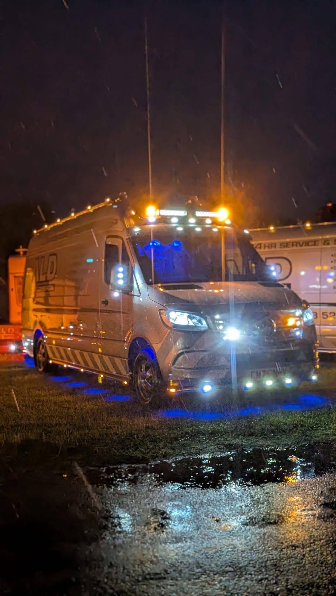 An ALD Mercedes Sprinter van lit up in amber and blue on a rainy night job