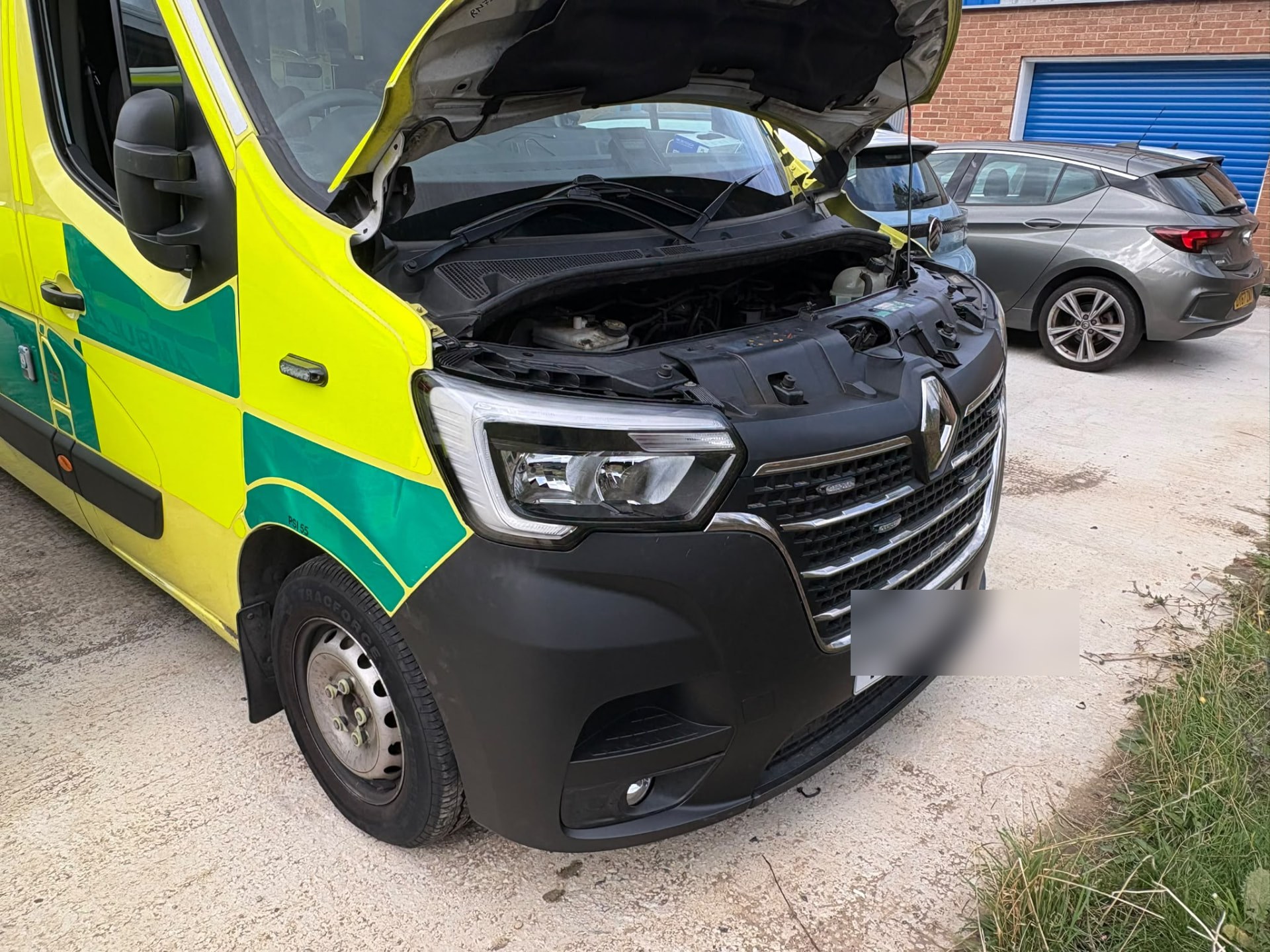 A yellow ambulance with the bonnet open during a repair visit