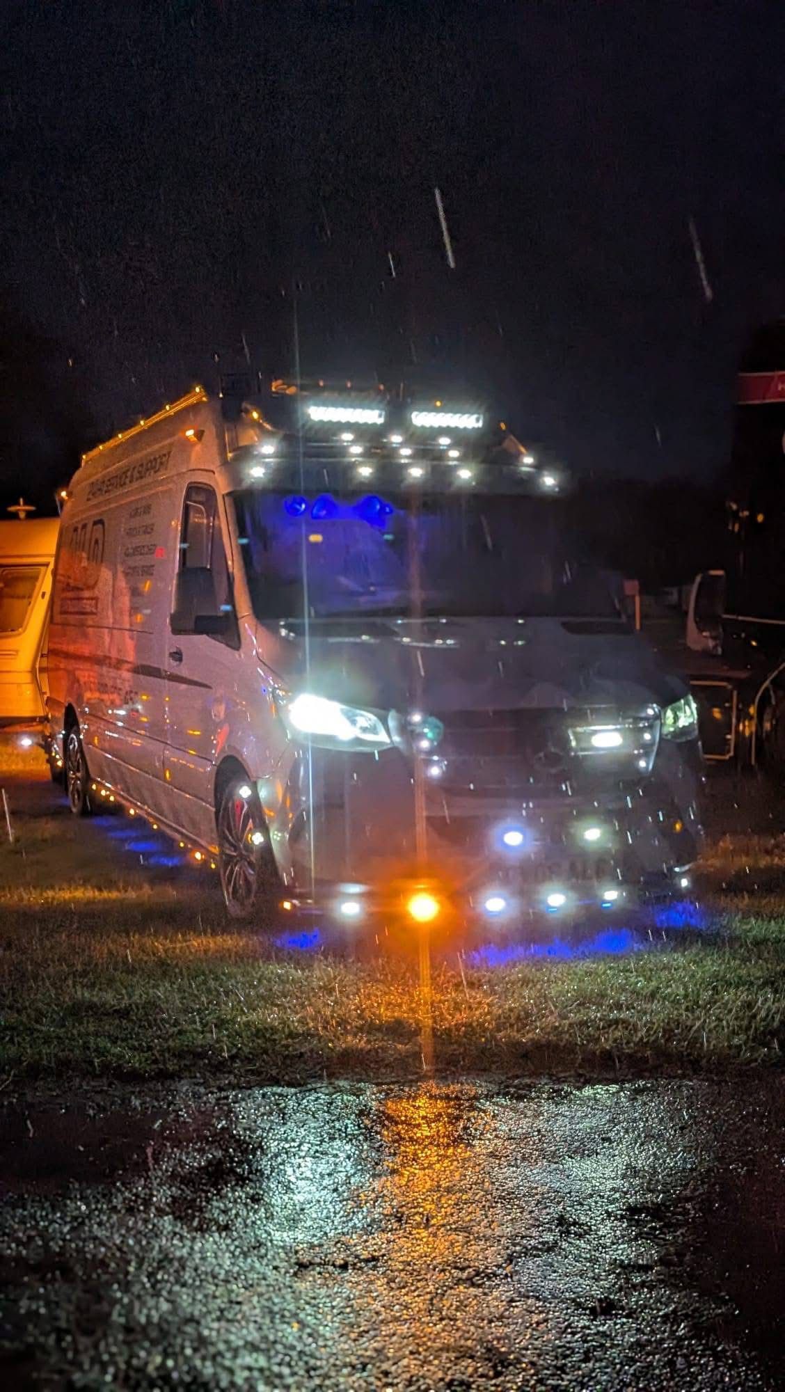 An ALD Mercedes Sprinter service van with work lights blazing in the rain at night