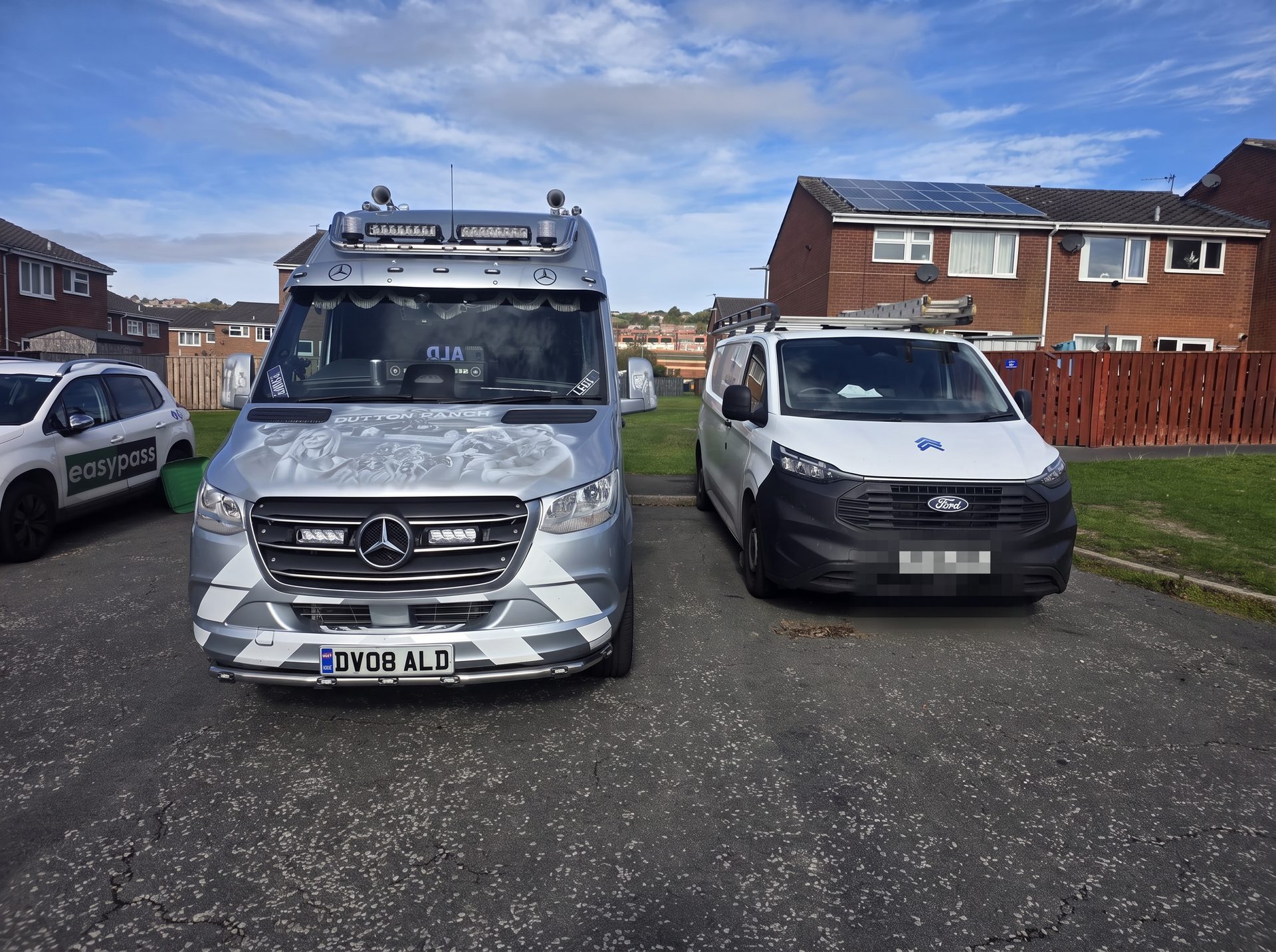 An ALD van parked next to a white Ford Transit Custom on a housing street